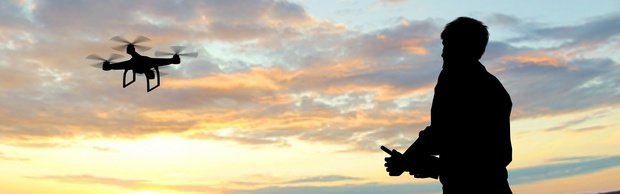 man operating of flying drone quadrocopter at sunset